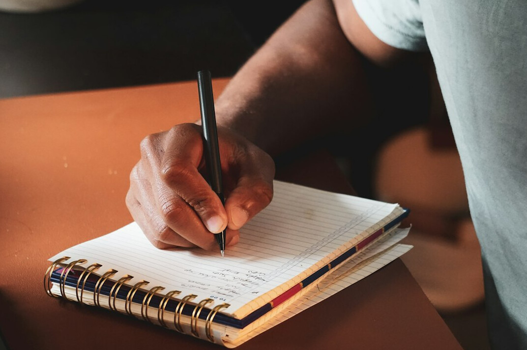 person writing notes in journal