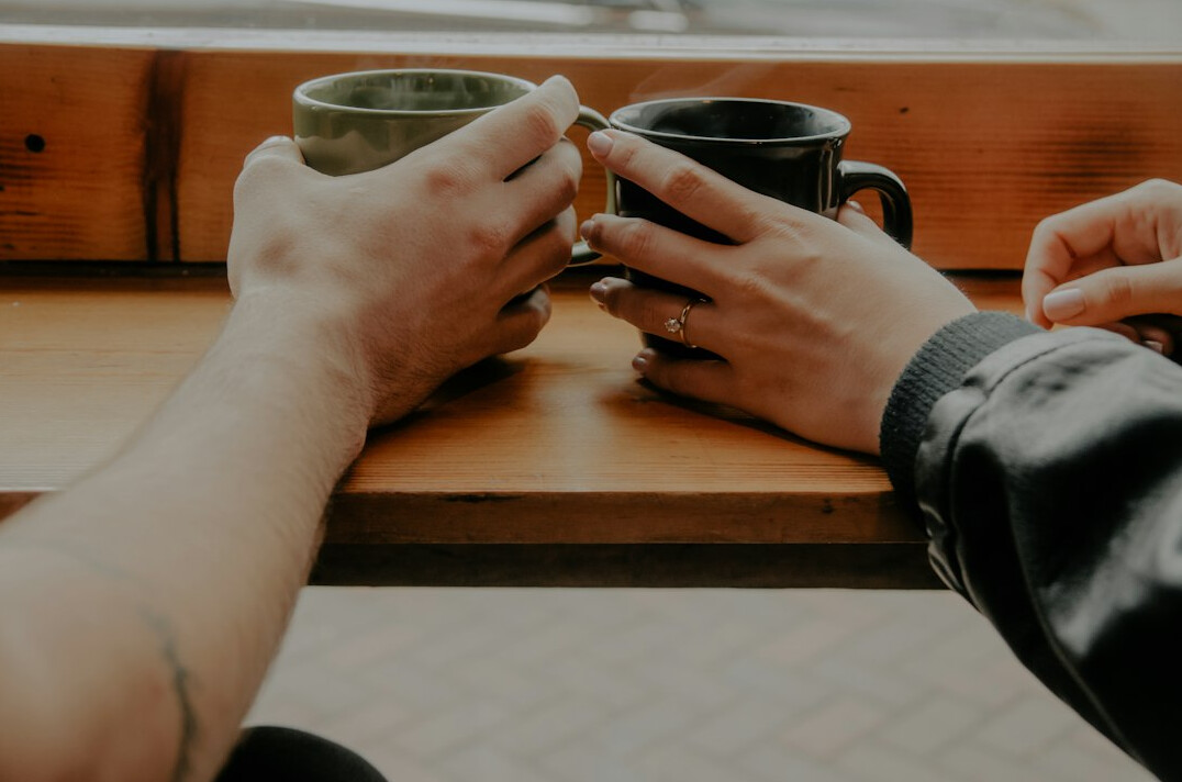 Two people having a warm supportive conversation over coffee